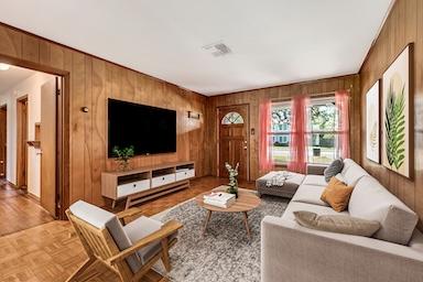 living area featuring visible vents and wood walls
