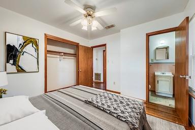 bedroom featuring ceiling fan, a closet, ensuite bath, and wood finished floors