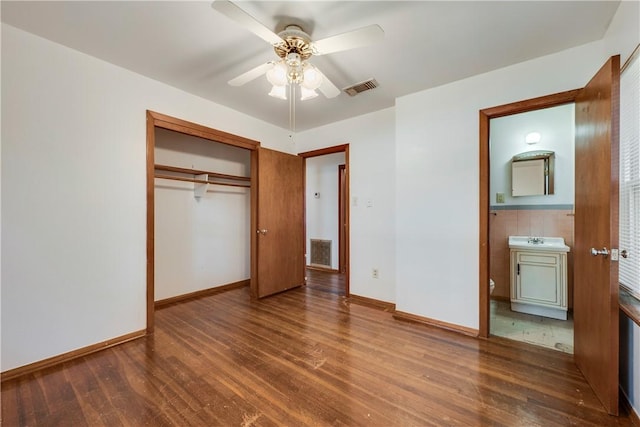 unfurnished bedroom with visible vents, wood finished floors, and a closet