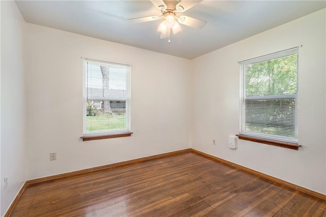 empty room featuring baseboards, ceiling fan, a healthy amount of sunlight, and dark wood-style floors
