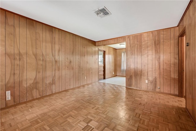 unfurnished room featuring visible vents, wood walls, and baseboards
