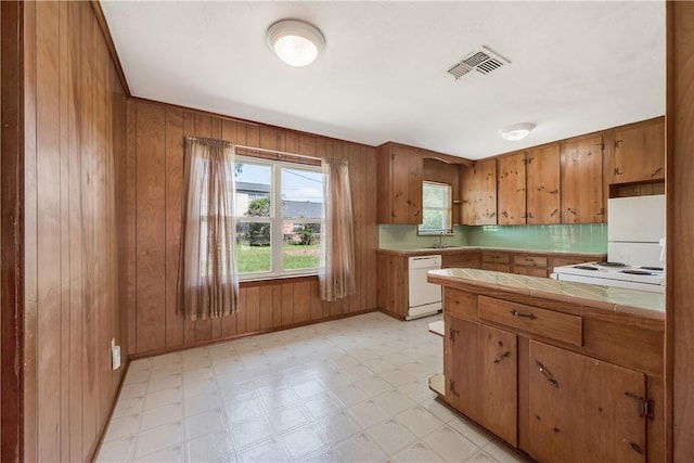 kitchen with brown cabinetry, tile countertops, visible vents, a sink, and white appliances