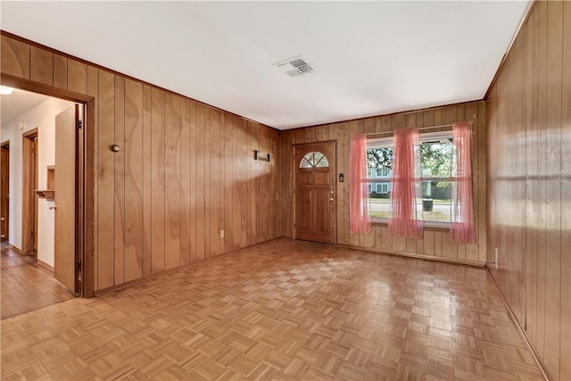 entryway featuring wooden walls, baseboards, and visible vents