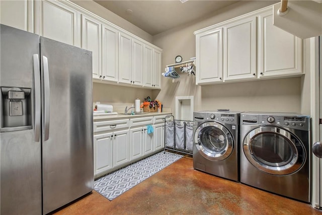 clothes washing area featuring sink, washing machine and dryer, and cabinets