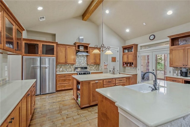 kitchen featuring sink, wall chimney range hood, appliances with stainless steel finishes, hanging light fixtures, and an island with sink