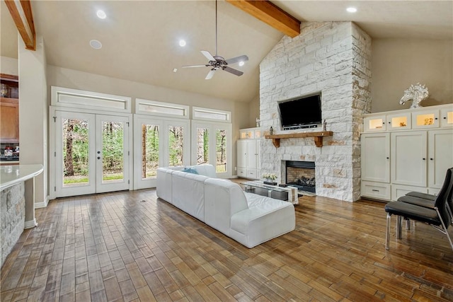 unfurnished living room featuring dark wood-type flooring, ceiling fan, beam ceiling, high vaulted ceiling, and a stone fireplace