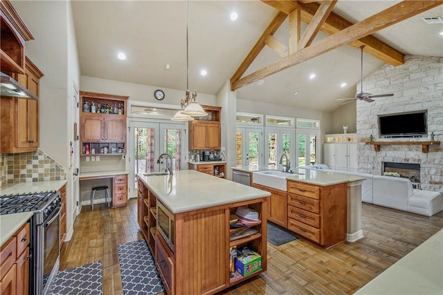 kitchen with pendant lighting, gas range, a kitchen island with sink, and french doors