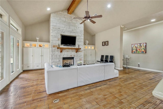 unfurnished living room featuring high vaulted ceiling, light wood-type flooring, beamed ceiling, ceiling fan, and a fireplace