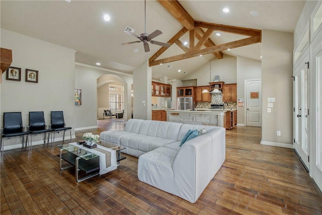 living room featuring dark hardwood / wood-style flooring, beam ceiling, high vaulted ceiling, and ceiling fan