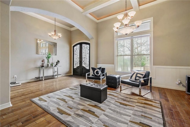 entrance foyer with crown molding, hardwood / wood-style floors, coffered ceiling, a notable chandelier, and beamed ceiling