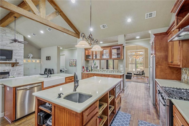 kitchen with pendant lighting, appliances with stainless steel finishes, sink, and a kitchen island with sink