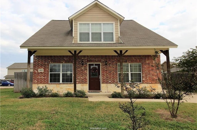 view of front of home with a shingled roof, a front lawn, and brick siding