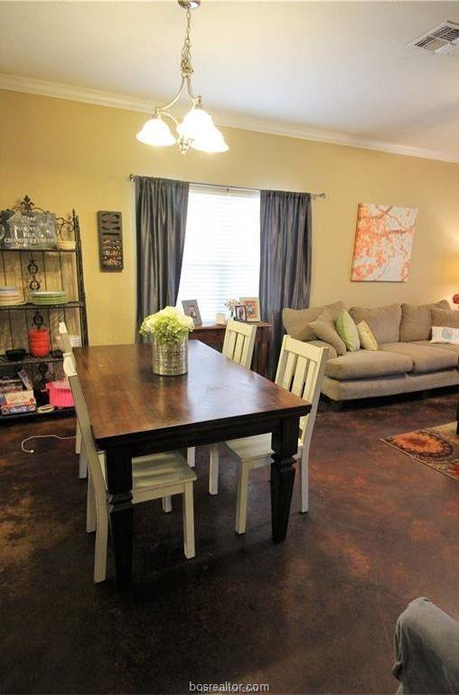 dining area featuring crown molding, visible vents, and a notable chandelier