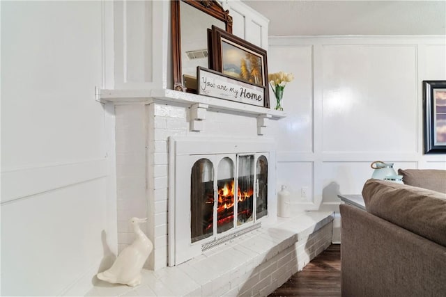 interior space with visible vents, wood finished floors, a fireplace, and a decorative wall