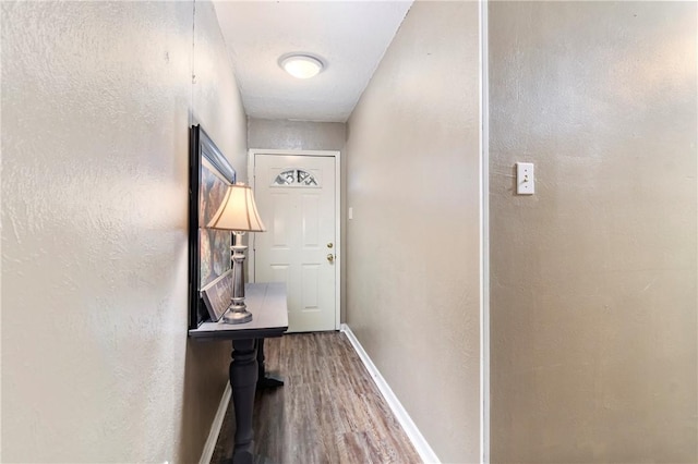 entryway featuring a textured wall, baseboards, and wood finished floors