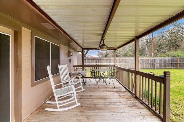 wooden terrace featuring a yard, outdoor dining space, and a fenced backyard