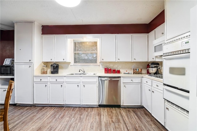 kitchen featuring a sink, a warming drawer, light countertops, and stainless steel dishwasher