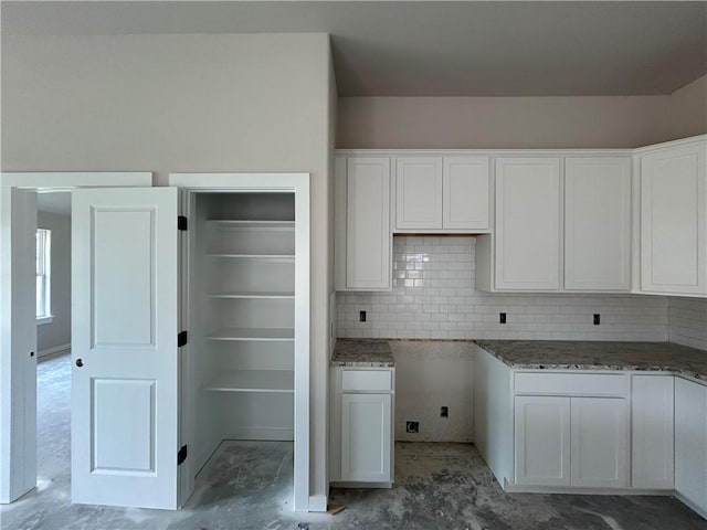 2814 Messenger Way, Bryan, TX 77802 - kitchen with concrete flooring, white cabinets, tasteful backsplash, and stone countertops