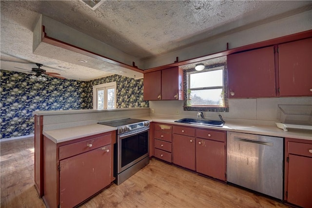 kitchen with appliances with stainless steel finishes, kitchen peninsula, ceiling fan, a textured ceiling, and sink