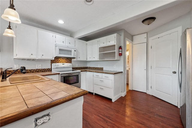 kitchen with white appliances, sink, decorative light fixtures, dark hardwood / wood-style floors, and white cabinetry