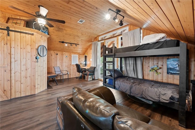 bedroom featuring vaulted ceiling, a barn door, wooden ceiling, hardwood / wood-style floors, and wood walls