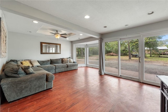 living room with wood-type flooring, a textured ceiling, a raised ceiling, and ceiling fan