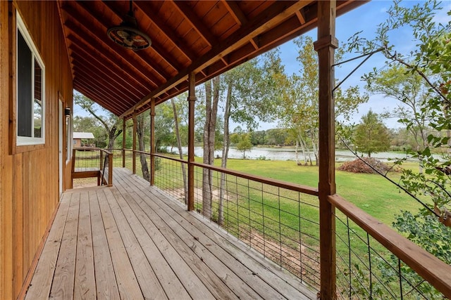 wooden terrace with a yard and a water view