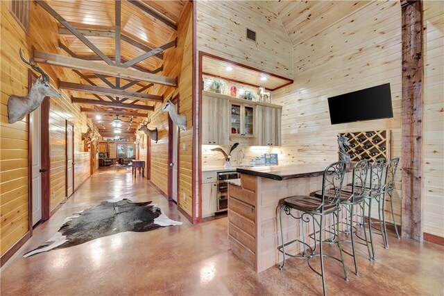 15184 Fm 2620, Bedias, TX 77831 - kitchen featuring wine cooler, concrete flooring, wooden walls, a breakfast bar area, and glass insert cabinets