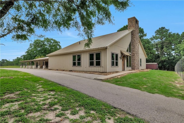 15184 Fm 2620, Bedias, TX 77831 - view of side of property featuring a chimney, a yard, board and batten siding, and a metal roof