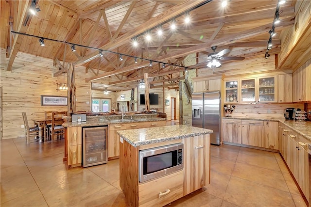 15184 Fm 2620, Bedias, TX 77831 - kitchen with wine cooler, stainless steel appliances, light brown cabinets, wood walls, and a large island