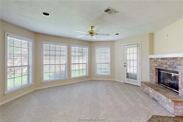 unfurnished living room with a fireplace, a textured ceiling, light colored carpet, and ceiling fan