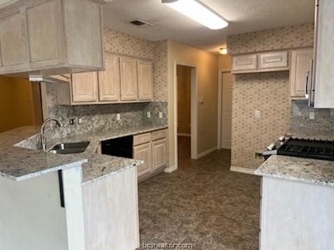 kitchen with range, sink, black dishwasher, light stone counters, and kitchen peninsula