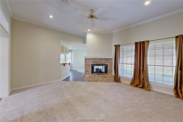 unfurnished living room with a brick fireplace, crown molding, carpet floors, and ceiling fan