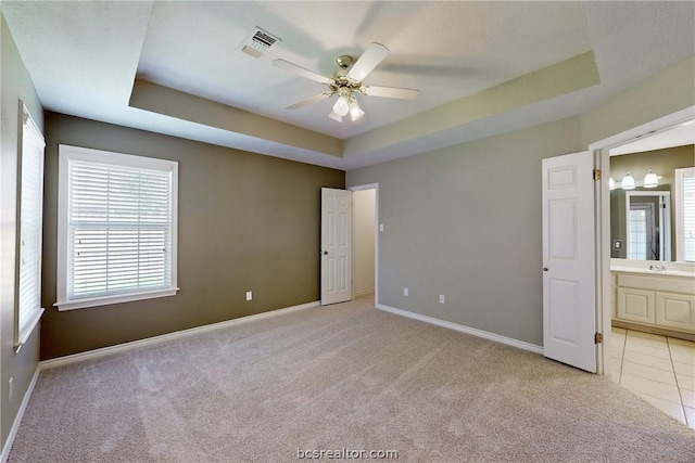 carpeted empty room with a tray ceiling and ceiling fan