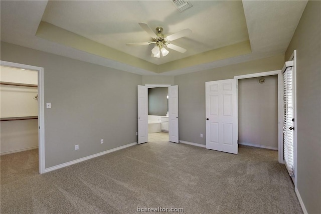 unfurnished bedroom featuring light carpet, a tray ceiling, and ceiling fan