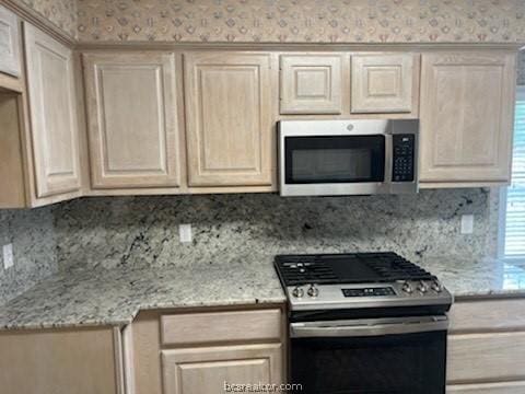 kitchen featuring light stone countertops, appliances with stainless steel finishes, and tasteful backsplash