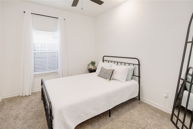 bedroom featuring light carpet, a ceiling fan, and baseboards