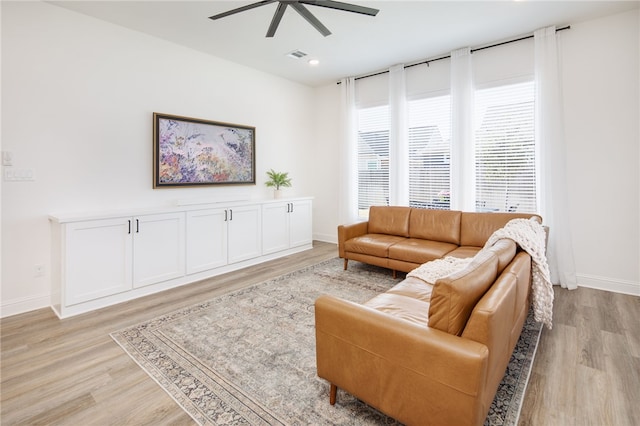 living area featuring light wood-style floors, ceiling fan, visible vents, and baseboards