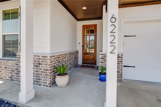 doorway to property with a garage and brick siding