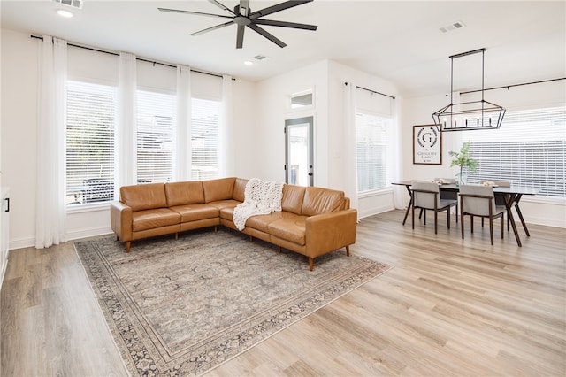 living area featuring a wealth of natural light, visible vents, light wood-style flooring, and baseboards