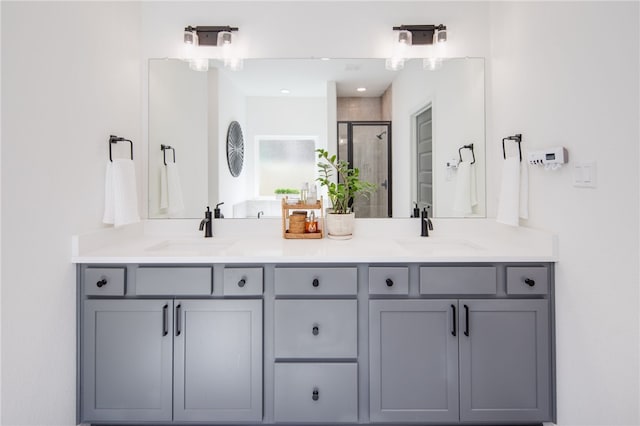 full bathroom with double vanity, a stall shower, and a sink