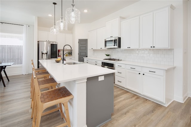 kitchen featuring an island with sink, appliances with stainless steel finishes, light countertops, and white cabinets