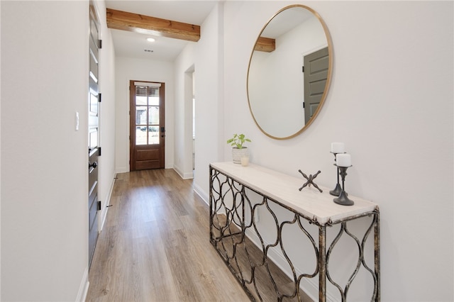 foyer entrance featuring baseboards, beamed ceiling, and light wood-style floors