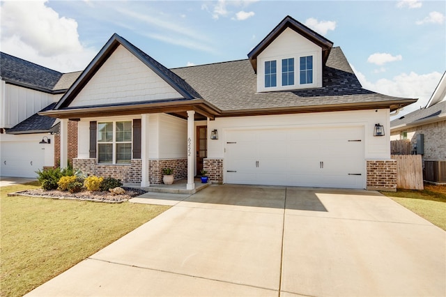 craftsman inspired home with a garage, a front lawn, concrete driveway, and brick siding