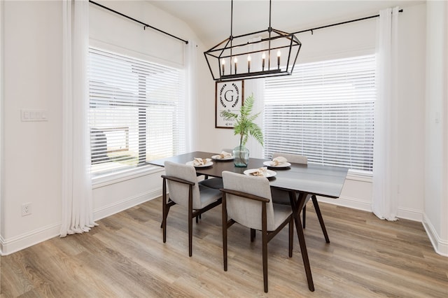 dining room featuring light wood-type flooring, baseboards, and an inviting chandelier