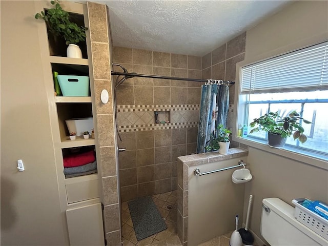 full bathroom featuring toilet, a walk in shower, and a textured ceiling