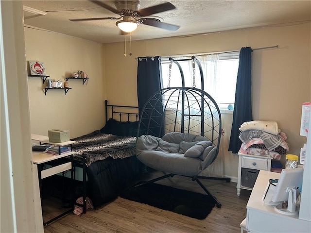 bedroom with a textured ceiling, ceiling fan, and wood finished floors