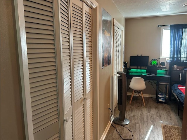 home office featuring baseboards, a textured ceiling, and wood finished floors