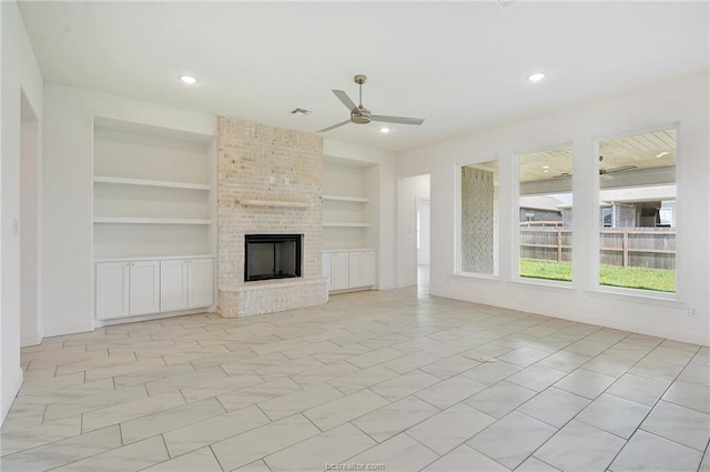 unfurnished living room with built in shelves, a fireplace, and ceiling fan