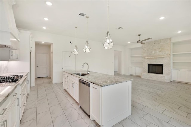 kitchen featuring sink, appliances with stainless steel finishes, white cabinetry, an island with sink, and decorative light fixtures